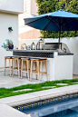 An outdoor bar island boasts decorative blue Spanish tiles that trim the outer lining of the white concrete bar under the dine in cement countertop.