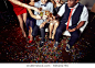 High angle view of unrecognizable group of friends toasting with champagne flutes while celebrating momentous event at night club, floor covered with colorful confetti