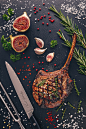Grilled pork chop tomahawk on slate board with figs and herbs
