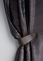 The flexible and versatile magnetic tie-back CORDONE is available in two basic colors. Two magnets are subtly inserted from the inside into the hand-sewn faux leather, allowing curtains to be gathered simply and attractively. The stitching, which can be c