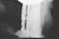 grayscale photo of man facing waterfalls
