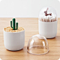 Q tip dispenser with a clear, dome-shaped cover and a small decorative figurine inside.