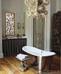 This master bath's tub-filler chandelier and laser-cut window panels are by Fisher Weisman; the tub and sink fittings are by Waterworks, and the Regency-style table is vintage.
