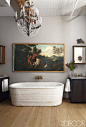 The master bathroom of Alice Childress and Christopher Daniels's downtown Manhattan loft, designed with the help of Courtnay Daniels Haden, includes an antique freestanding marble tub, a vintage Italian chandelier, and an inherited 18th-century painting. 