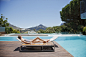 Woman sunbathing on lounge chair next to luxury swimming pool with mountain view by Caia Images on 500px