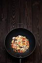 WOK: photo for poster : Round Chinese deep pan with a small diameter convex bottom filled with noodles, shrimps, mushrooms, peppers, peas and corn for a tasty poster.