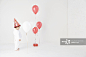 Baby girl (15-18 months) wearing party hat standing in studio, looking at balloons and present_创意图片