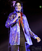 在这张照片中，可以看到洋溢着笑脸的迈克尔·杰克逊身着一件发光的雨衣外套，手中握着话筒。