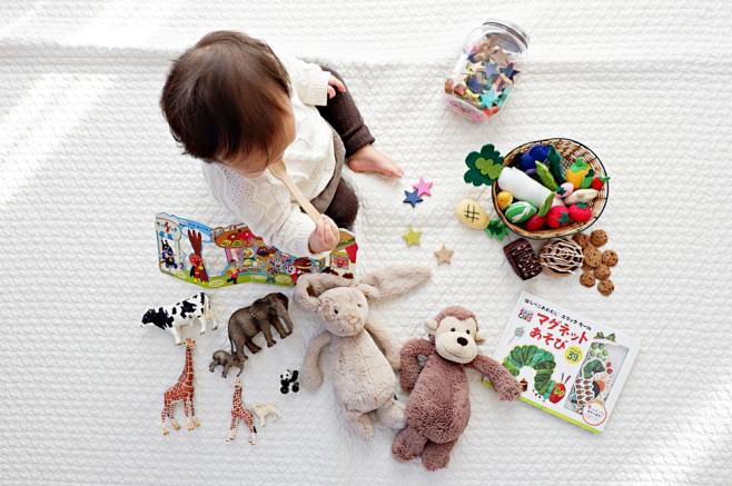 男孩坐在被玩具包围的白布上