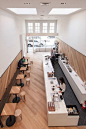 A curved serving counter clad with a honeycomb pattern of white tiles occupies the front space of this cafe in San Francisco, California.