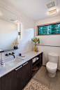 White subway tiles and a dark vanity with some open shelves have been used in the design of this bathroom