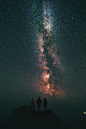 Three people staring at a vibrant starry night sky.