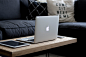 A MacBook, an iPad and an iPhone on a coffee table by a sofa