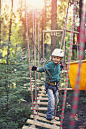 Little boy walking on ropes course in outdoors adventure park