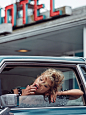 Stella Maxwell poses in a car wearing a polka dot print off-the-shoulder dress