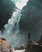 免费 男子站在瀑布摄影前的棕色岩石悬崖上 素材图片