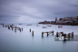 England, Dorset, Swanage. The timber remains of the Old Pier at Swanage, and the Wellington Clock Tower in the background, which originally stood at the southern end of London Bridge.