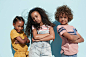 Portrait of 3 cool kids together on blue backdrop in summer