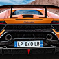 The image shows a rear view of an orange Lamborghini Huracán Performante as it speeds through a desert landscape.