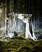 将花边窗帘和假花固定在杆子上，制作一个DIY快照亭背景，悬挂起来装饰森林婚礼