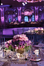 Centerpieces of purple blooms compliment the striped table linens that don a similar hue.