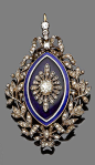 An enamel and diamond brooch/pendant, circa 1910. The navette-shaped plaque decorated royal blue and white guilloché enamel, set to the centre with an old brilliant and rose-cut diamond flowerhead, within an openwork wreath tied with ribbons and set throu