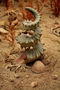 这个成了精的羚羊角，是生活在白垩纪同恐龙一起灭绝的一种勾菊石，Helioceras heteromorph，的复原图。 菊石是一群曾经极度繁盛的头足纲动物，与恐龙一同灭绝。与外观相似的鹦鹉螺相比，它们更加接近乌贼和章鱼。不同的是它们保留了一个螺旋的贝壳，通常是卷在一个平面上的螺旋，流线型有助于快速游泳，但是各类勾菊石都是异形菊石，往往有奇怪的形状，猜测它们是浮游的或者底栖的。 与海螺不同，菊石的后半段是空腔，用来改变浮力，功能相当于鱼鳔