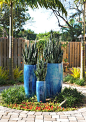 Bright blue pots accent a landscape designed by Pamela Crawford. See her work at pamela-crawford.com. Her services include landscape design and installation, pottery, outdoor furniture, and paving design. She covers Palm Beach County, including Boca Raton