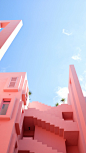 The pink exterior of a uniquely built building.