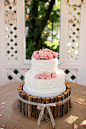 婚礼蛋糕用小木桩围了起来，纯白色奶油蛋糕上随意点缀了几朵粉色玫瑰，没有翻糖的精致和华丽，却多了几份质朴与纯真。