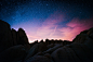 The sky full of stars with blue and pink hues over the rock formations.