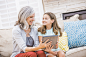 Caucasian grandmother and granddaughter using digital tablet on sofa by Gable Denims on 500px