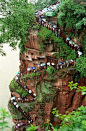 中国游客正在等待在雨中看到佛像最大的坐姿雕像。地点 - 乐山，Sechuan，中国