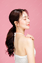 Young asian woman gathered in ponytail with natural makeup on face have plump lips and clean fresh skin wearing white camisole on isolated pink background portrait of cute female model in studio