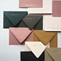 Envelopes in spruce green, olive green, pink, ochre, cream, and black.