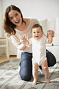 Mother helping baby stand in living room by Gable Denims on 500px