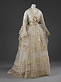 The dress is of cream silk gauze with narrow opaque stripe, and trimmed with cream silk embroidered net lace. A three-quarters length bodice...