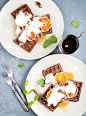 Belgian soft waffles with blood orange, cream, marple syrup and mint  on white plates