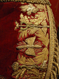 Crimson silk gentleman’s Court Dress, French, Second Empire. The gold bullion embroidery contains images of the Wand of Asclepius surmounted by the Empress Eugenie’s crown, a winged thunderbolt of Jupiter, and a Caduceus surmounted with the winged cap of 
