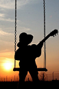 Little boy playing guitar while the sun sets