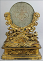 JAPANESE SILVERED BRONZE MIRROR ON LACQUER STAND, MEIJI PERIOD, composed of a silvered bronze hand mirror cast with kiri mon (wisteria crest) on brocade ground and cast inscription, fitted in a lacquer wood base, with the mirror rising out of gold crestin