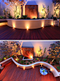 17 Inspiring Examples Where Exterior Uplighting Has Been Used To Show Off A House // Recessed lighting on this curved patio and inside the planters brighten the outdoor space and create a dramatic effect with the shadows behind the plants and metal instal