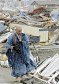 2011年4月4日上午，日本岩手县山田町，一位身披青袈裟、赤脚麻鞋的青年僧侣在漫天飞雪中踽踽独行，诵经祈祷。