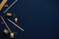 An overhead shot of pencils, a ruler, scotch tape and bulldog clips on a dark blue surface