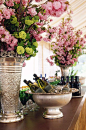An impeccably arranged champagne bar rests between two metallic urns filled with colorful fresh florals.