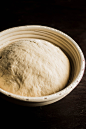 Bread dough rising in a proofing basket on a dark background