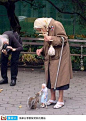 街头暖心一景:老奶奶操控着一只“老奶奶”提线人偶,为小松鼠喂食