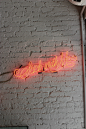 A red neon with “stick with me” written in cursive on a white brick wall