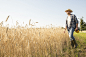 Man wearing a checked shirt and a hat standing in a cornfield, a farmer. by Mint Images on 500px