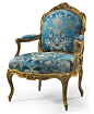 A LOUIS XV GILTWOOD FAUTEUIL A LA REINE  BY JEAN-JACQUES POTHIER, MID-18TH CENTURY  With a cartouche-shaped upholstered backrest carved with ribbon-tied laurel leaves at the cresting, with padded armrests on raised volute supports, the serpentine seatrail